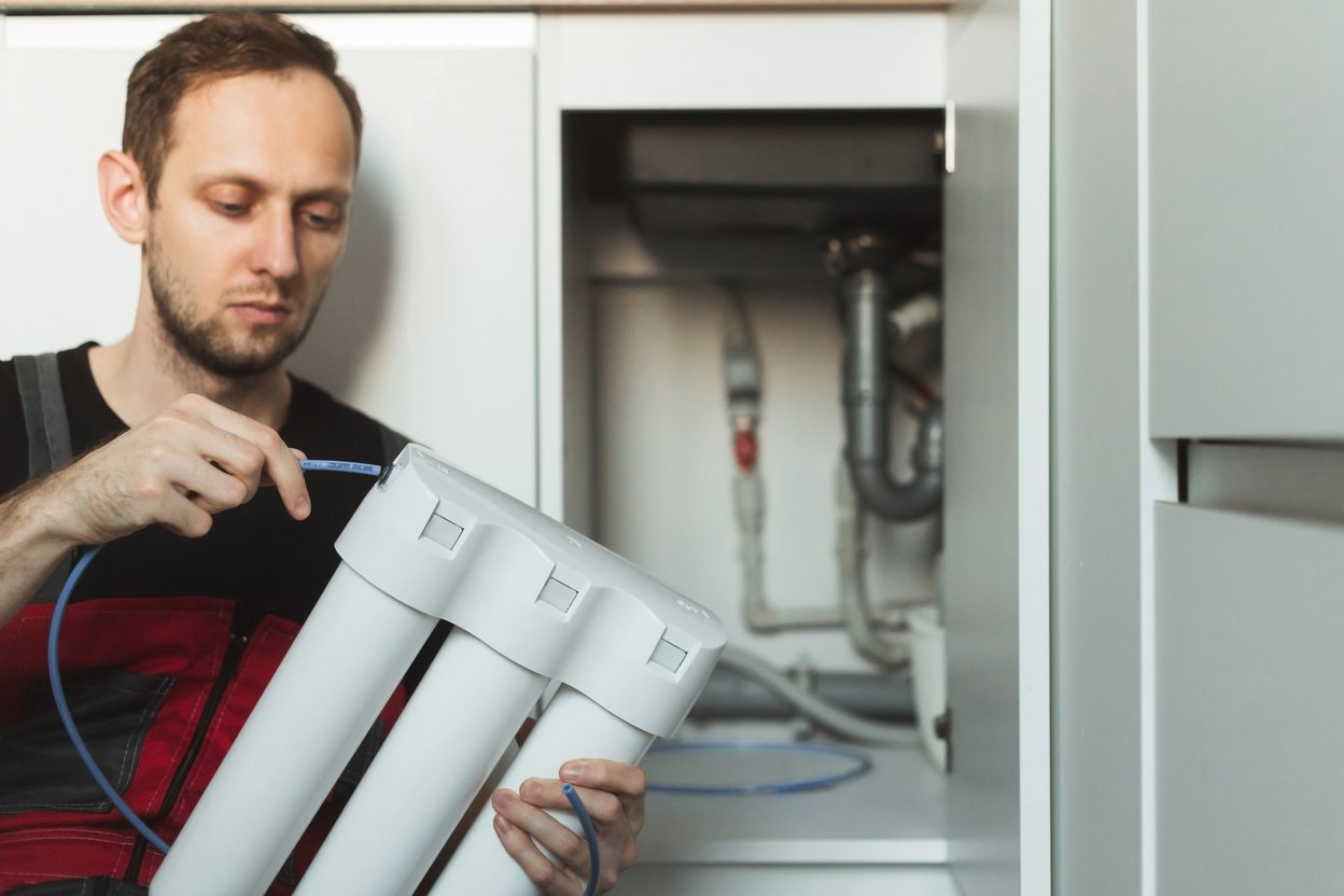 Plumber in the Kitchen Installs a Household Water Treatment Syst